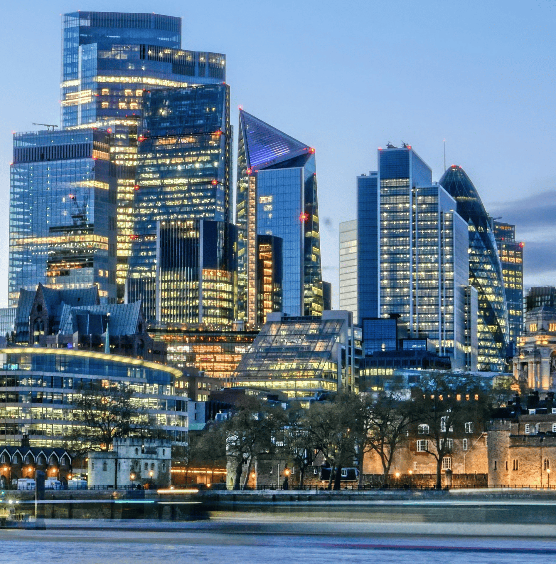 London financial district skyline at dusk with illuminated skyscrapers and River Thames in the foreground London financial district skyline at dusk with illuminated skyscrapers and River Thames in the foreground