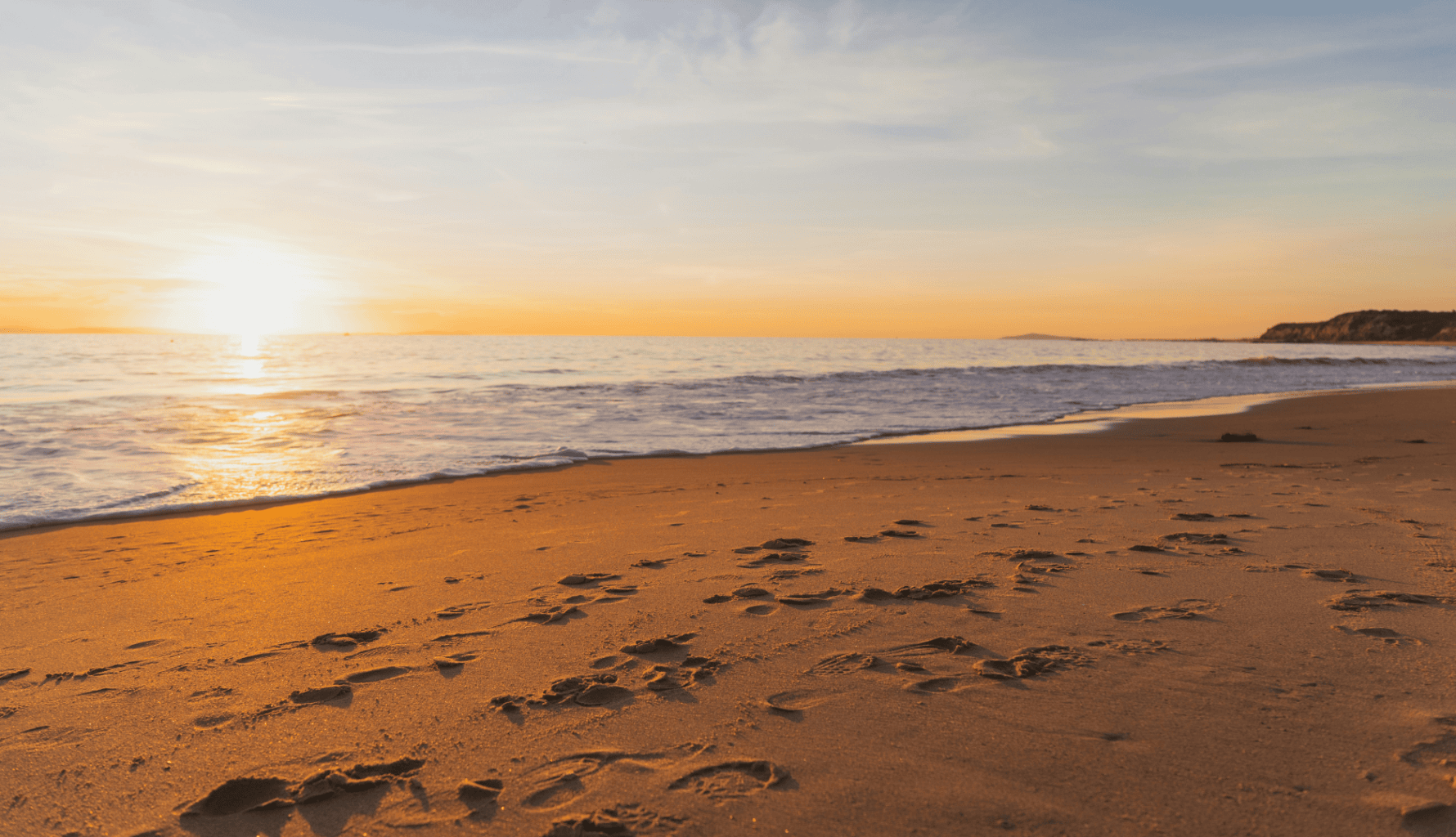 Footprints on a quiet shoreline at sunset, symbolising the unseen digital footprint and exposure risks faced by modern family offices Crisis24